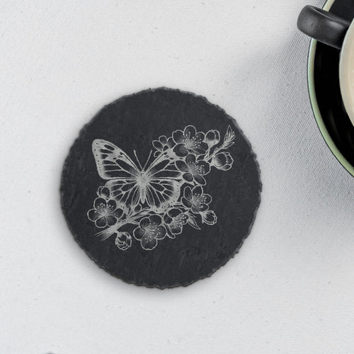 Round slate coaster laser engraved with a butterfly among cherry blossoms (product mockup)