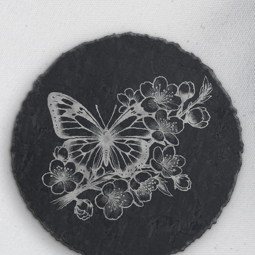 Close-up of the butterfly and blossom engraving on round slate (product mockup)