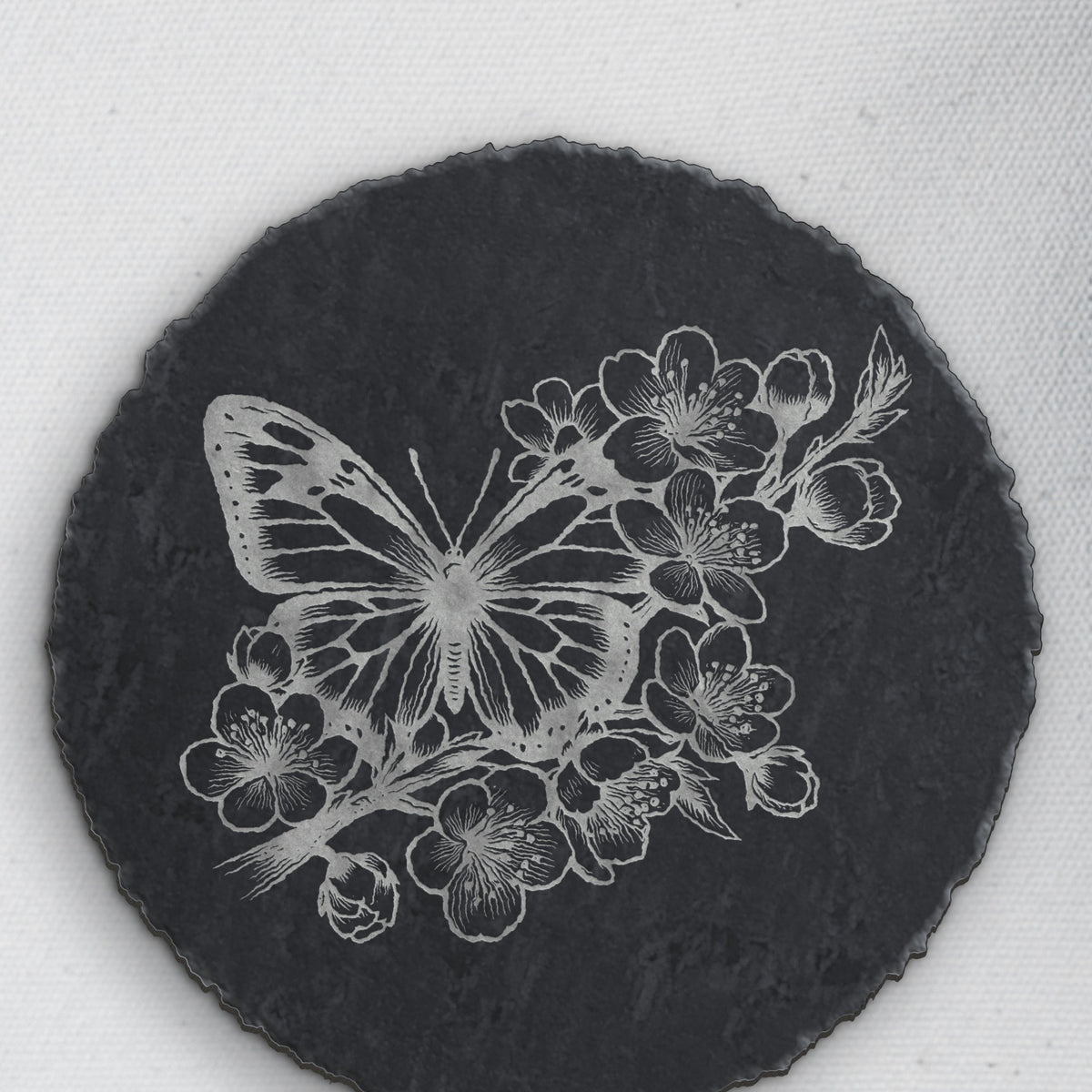 Close-up of the butterfly and blossom engraving on round slate (product mockup)