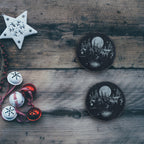 Two winter cabin slate coasters on a rustic wood table with holiday decorations (product mockup)