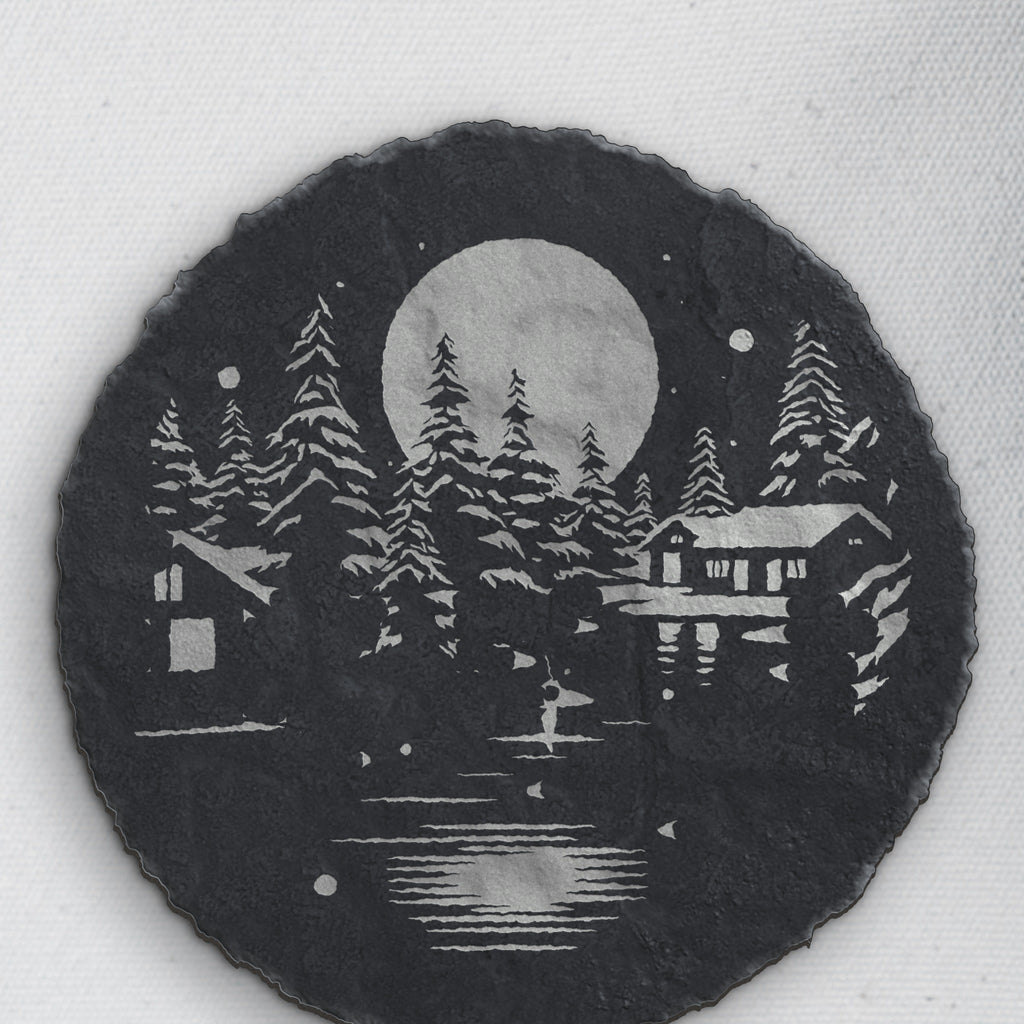 Close-up of the winter cabin engraving on round slate (product mockup)