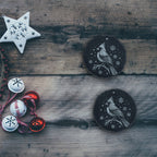 Two cardinal slate coasters on a rustic wood table with holiday decorations (product mockup)