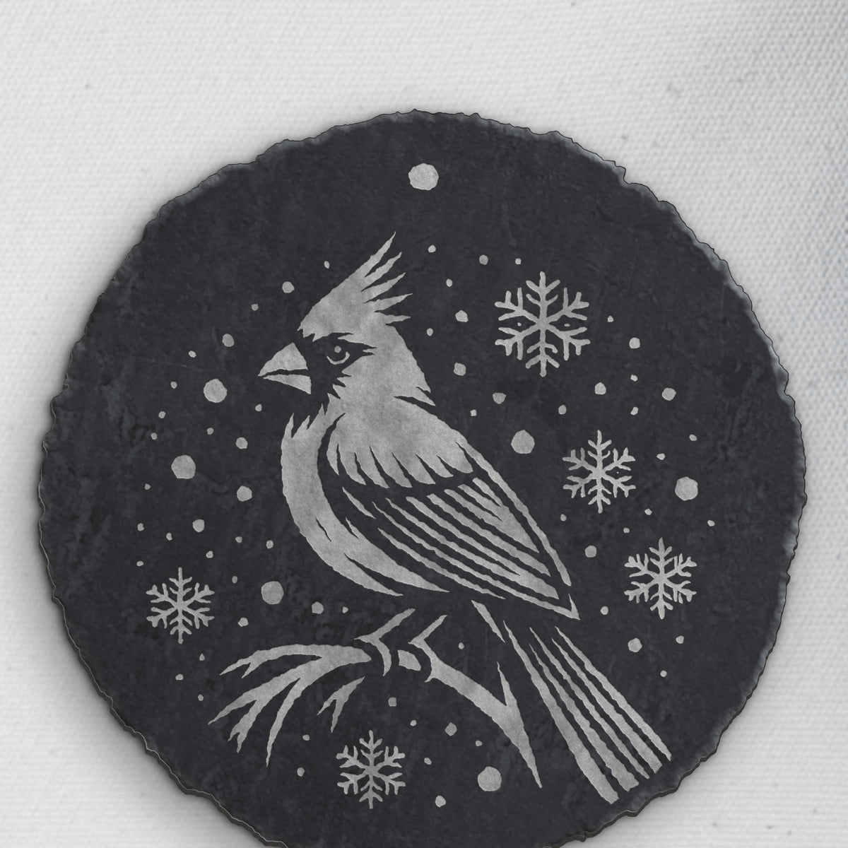 Cardinal in the snow design on round slate, one of the four coasters in the mixed set (product mockup)