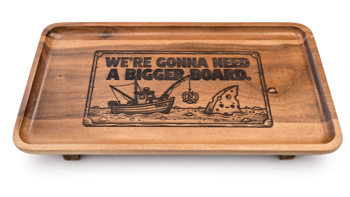 Acacia serving tray laser engraved with We're Gonna Need A Bigger Board, a fishing boat and a cheese-wedge fin (real photo of our work)