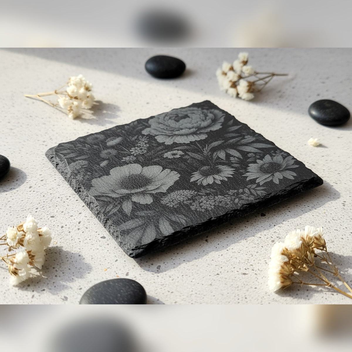 Square slate coaster engraved edge to edge with peonies and wildflowers, styled with dried flowers and stones