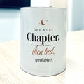 White 11oz mug, front view, printed "One more Chapter. then bed. (probably.)" in charcoal and terracotta with a small crescent moon.