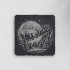 Square slate coaster engraved with Santa's sleigh flying past the moon over snowy pines (product mockup)