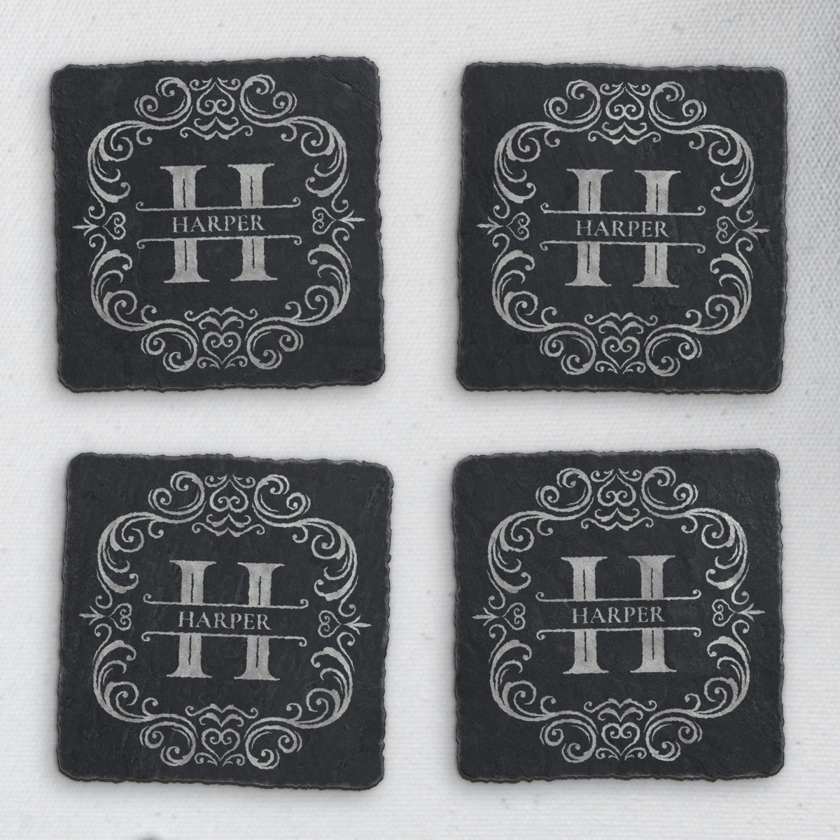 Four square slate coasters engraved with a split-letter H monogram and the sample name Harper (product mockup)