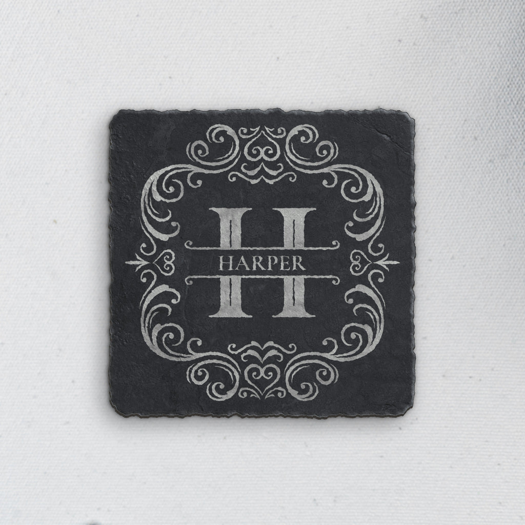 Square slate coaster engraved with an ornate split-letter H monogram and sample name Harper, natural gray engraving (product mockup)