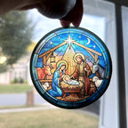 Nativity stained-glass-style ornament held up to a window so the light shines through