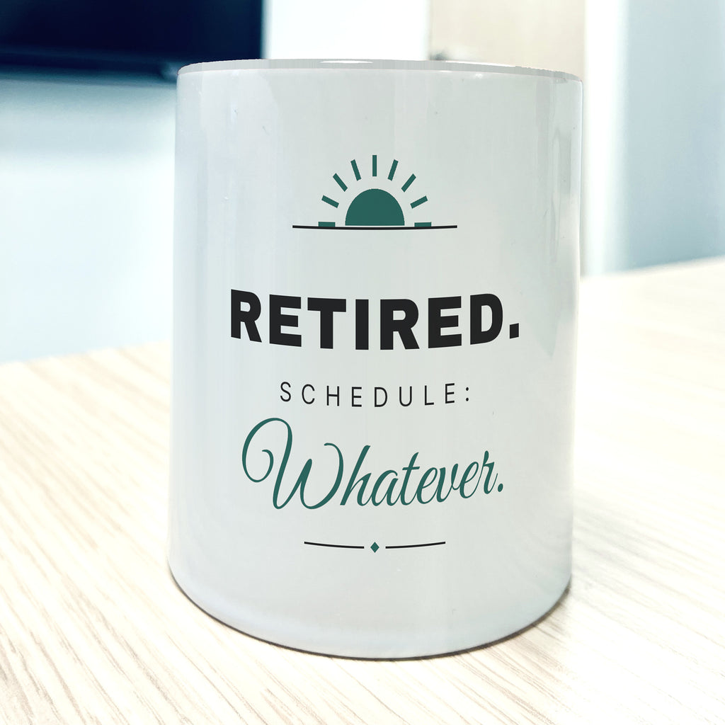 White 11oz mug, front view, printed "RETIRED. Schedule: Whatever." in charcoal and teal script under a small rising-sun mark.